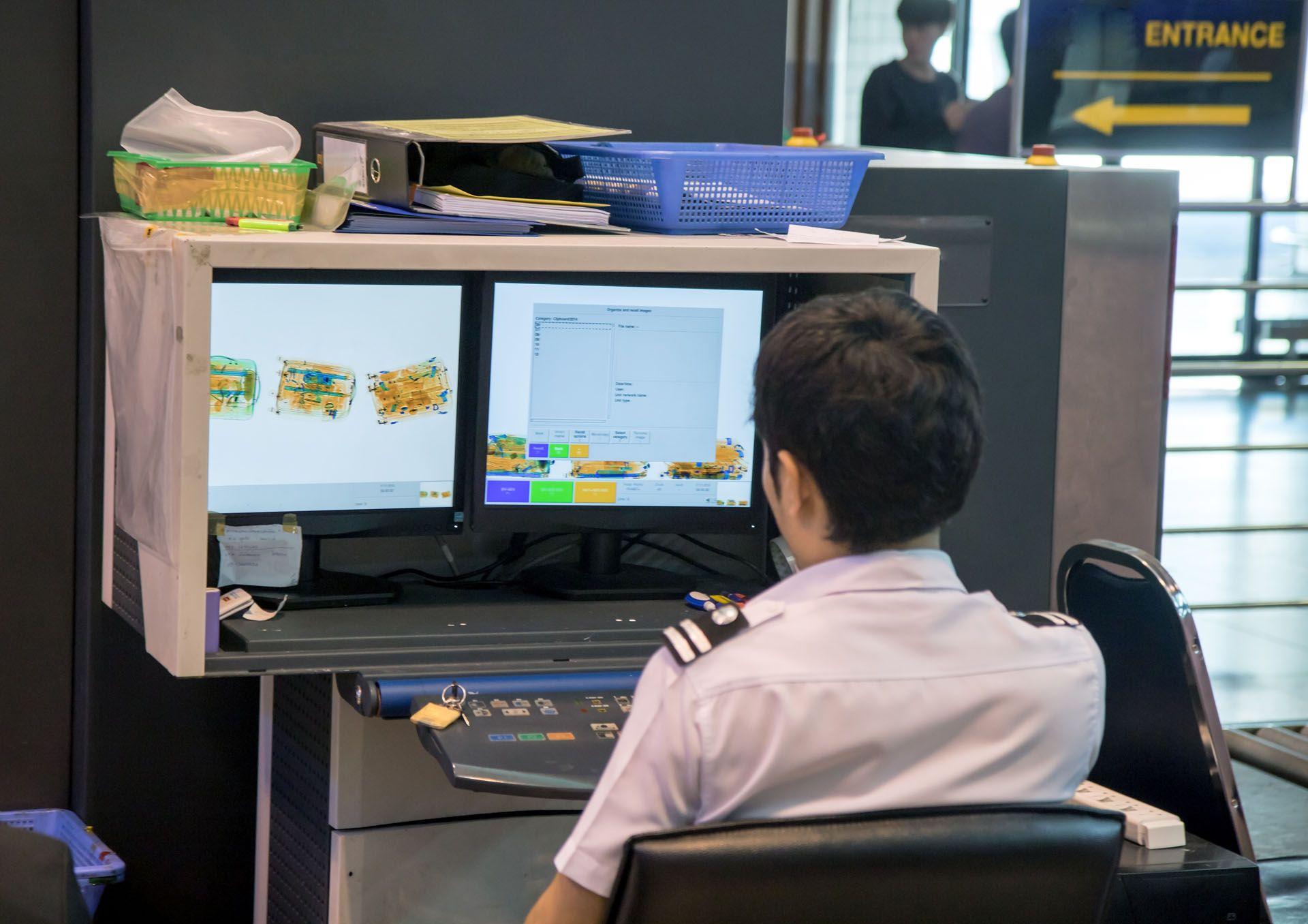 Un agent de constatation des douanes qui controle les bagages des passagers dans un aéroport