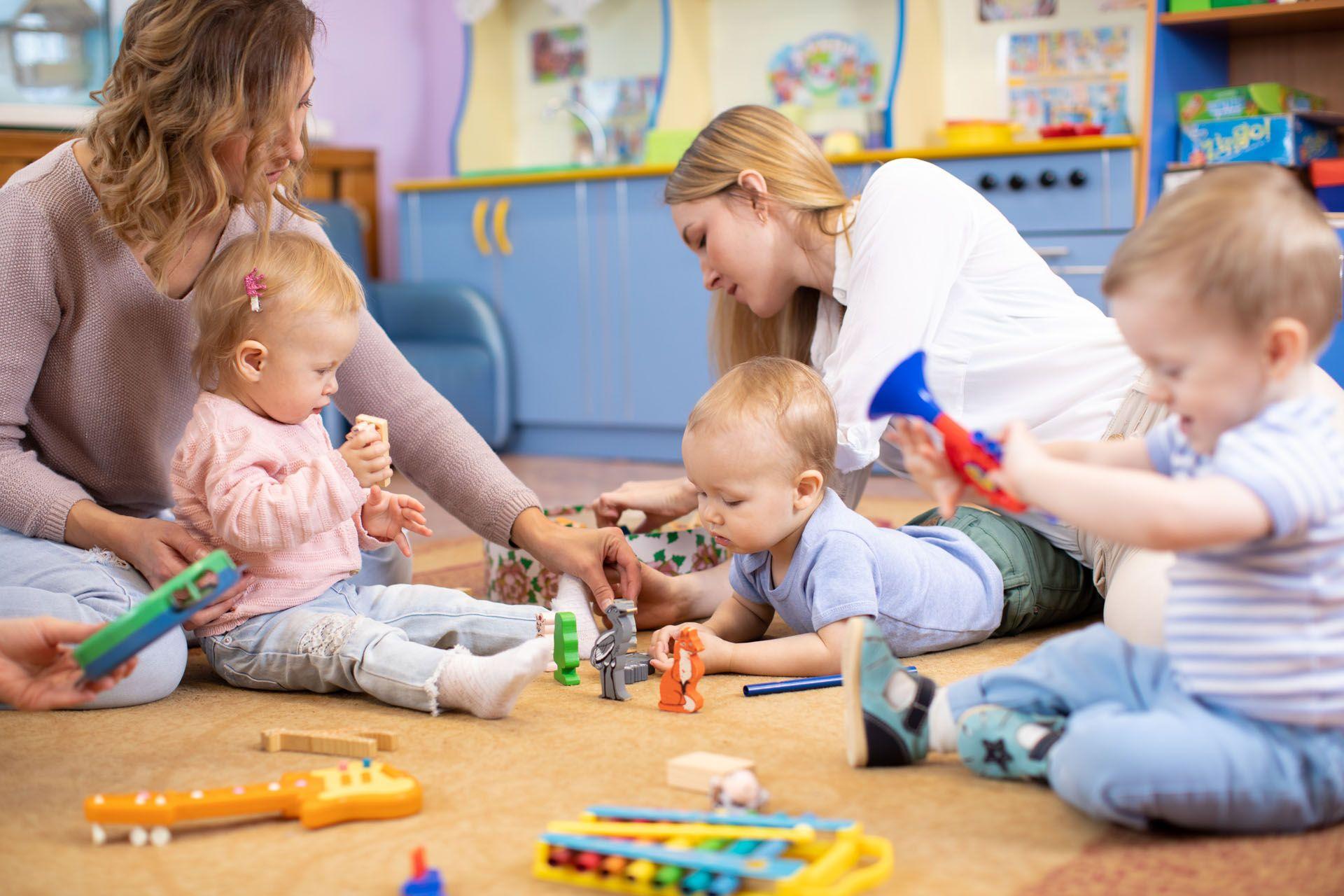 Des agents de crèche qui sont avec plusieurs enfants et leurs jouets