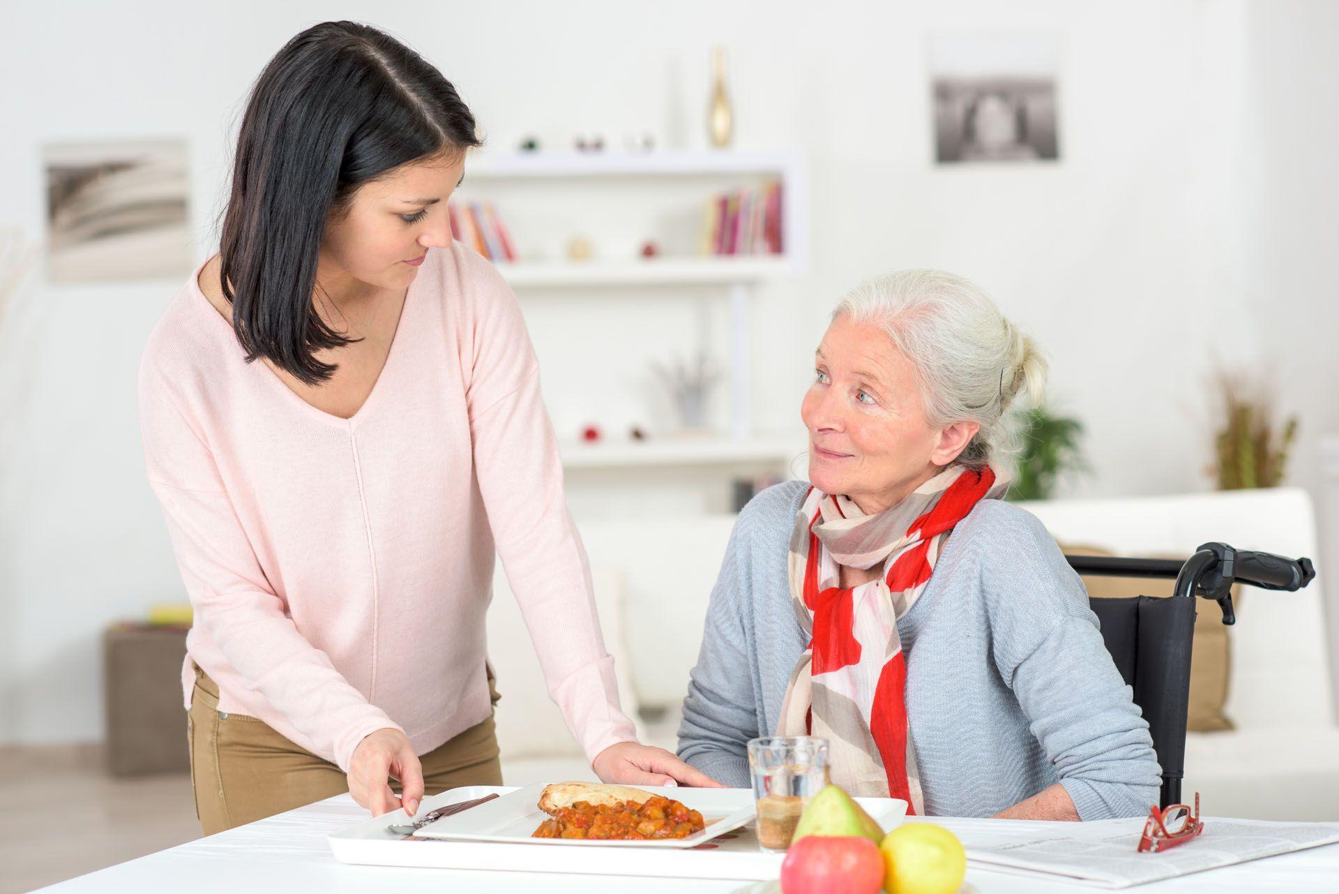 Une auxiliaire de vie qui aide une personne agée à se nourir