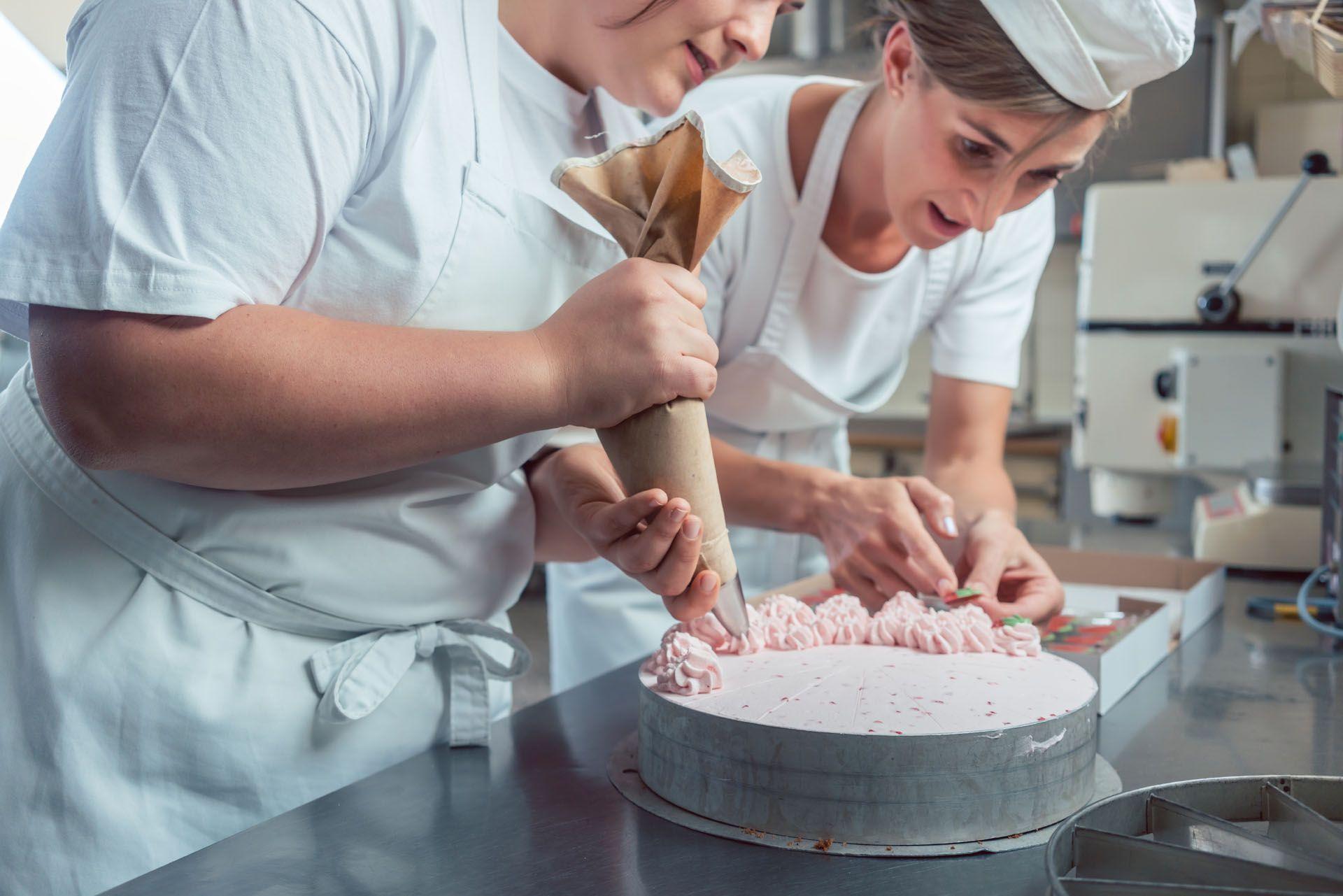 Deux patissières en cuisine qui terminent la préparation d'un gateau