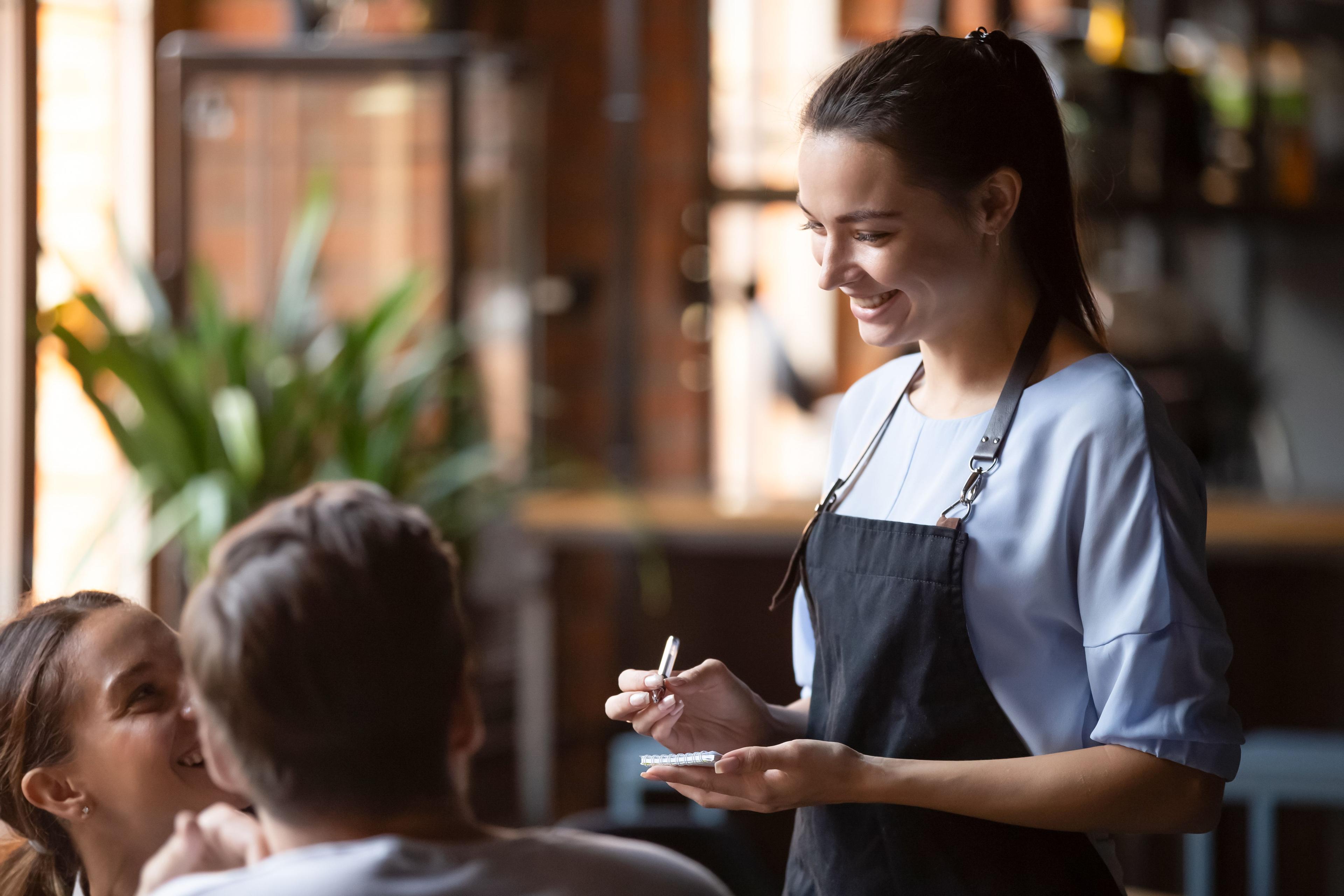 une serveuse note la commande de clients