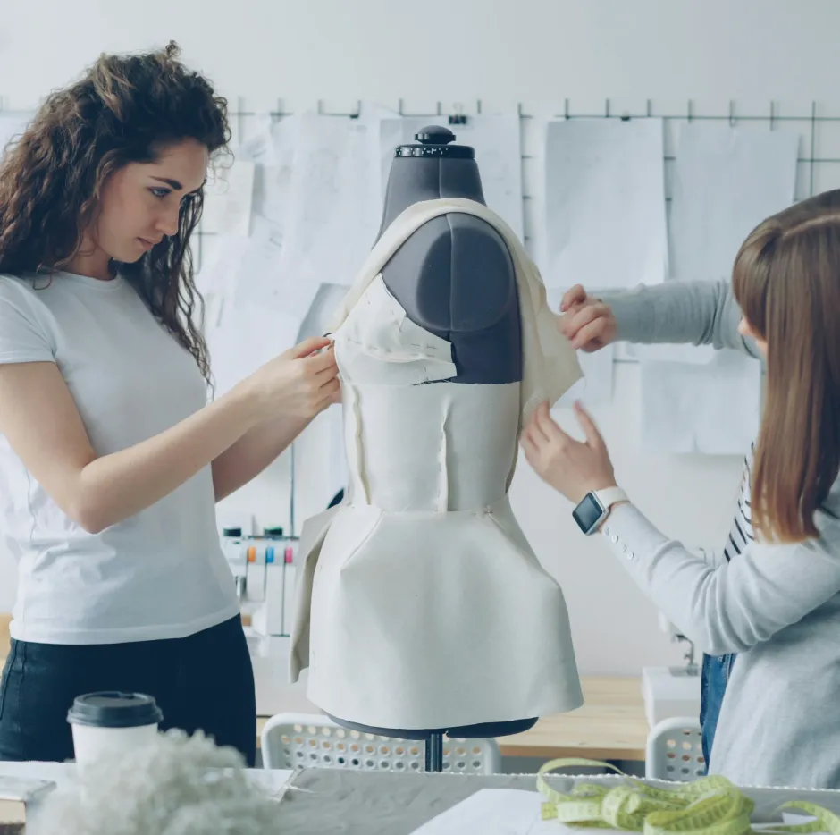 Deux femmes stylistes de mode sont en train de créer un vêtement sur un buste.
