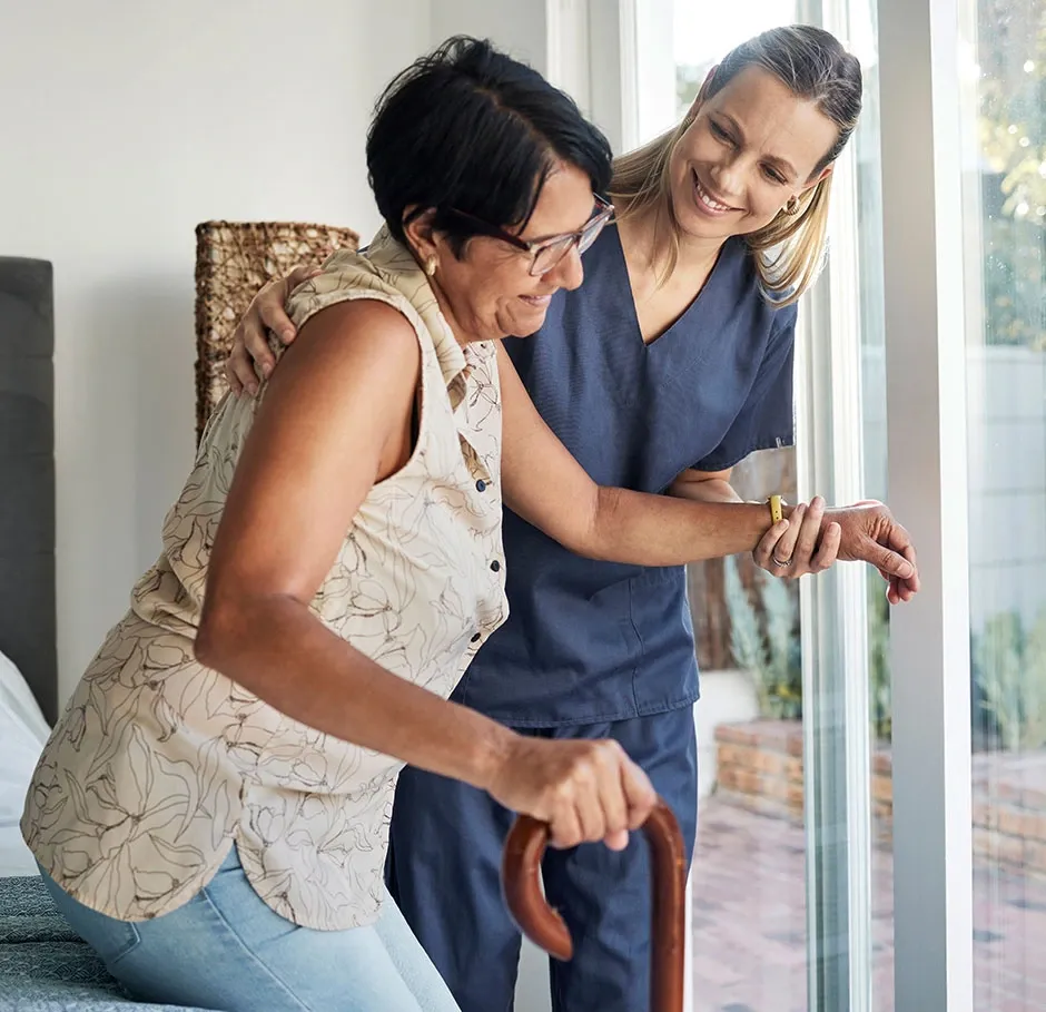 Apprenante en formation d’accompagnement à domicile aidant une personne en perte d’autonomie à se lever avec bienveillance